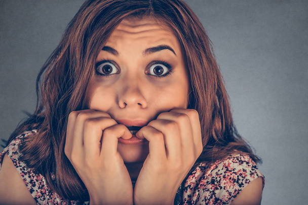 Closeup portrait headshot nervous stressed young woman girl employee student biting fingernails looking anxiously craving something isolated grey wall background. Human emotion face expression feeling - Foto, Imagen