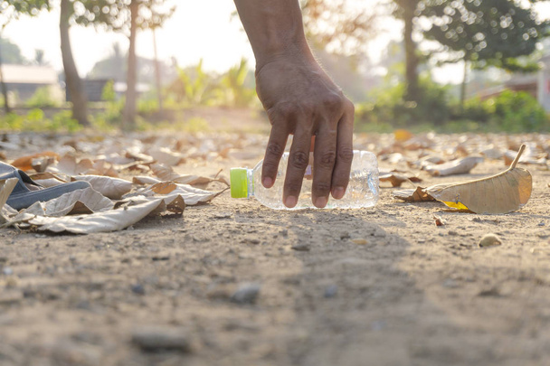 La mano de los hombres está recogiendo plástico en hojas secas molidas en otoño. De diciembre, Concepto de salvar la tierra
 - Foto, Imagen