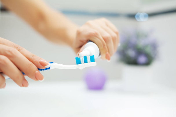 Zavřít ruce žena použít kartáček na zuby ve světlé koupelně - Fotografie, Obrázek