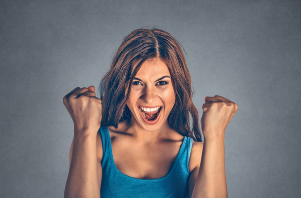 Excited woman holding fists up in triumph celebrating win and looking up happily. Mixed race model isolated on grey, gray background with copy space. Horizontal image. - Photo, image