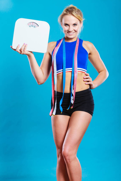 Fit woman with measure tape with weight scale - 写真・画像