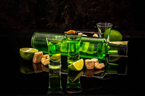 Absinthe or mint liquor shot. absinthe in glass with lime slices on dark background - Valokuva, kuva