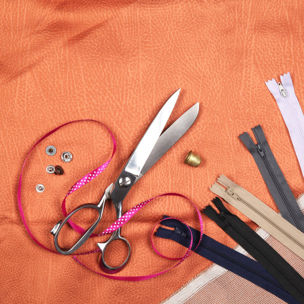 Ensemble d'outils et accessoires de couture sur tissu orange. Vue du dessus
 - Photo, image