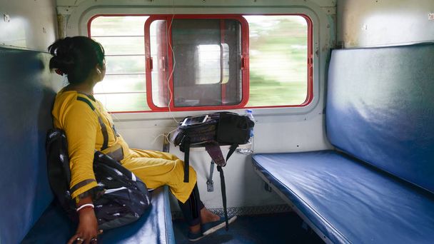 Frau hört Musik auf Handy und schaut aus dem Fenster, während sie allein im Zug unterwegs ist. Reisende, die moderne Technologie im Alltag und auf Reisen genießen. Seitenansicht Nahaufnahme por - Foto, Bild