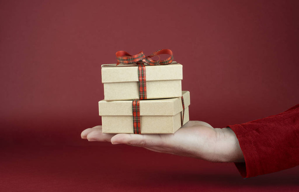 mano dell'uomo che tiene scatole regalo di San Valentino davanti a uno sfondo rosso
 - Foto, immagini