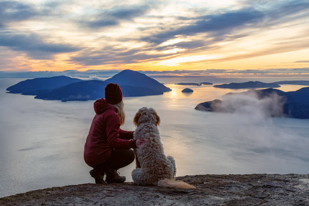 Adventurous Girl Hiking on top of a Mountain with a dog - Фото, изображение