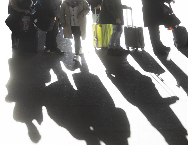 Тени людей, путешествующих с чемоданами под ярким солнцем
 - Фото, изображение
