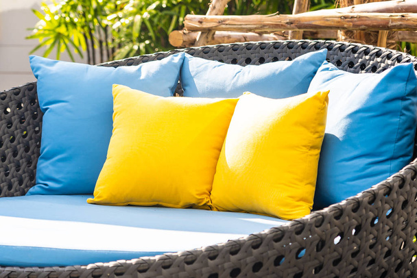 Открытый внутренний дворик в саду с диваном-стулом и декоративными подушками
 - Фото, изображение