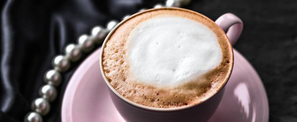Kuppi cappuccinoa aamiaiseksi satiinilla ja helmillä koruja
  - Valokuva, kuva