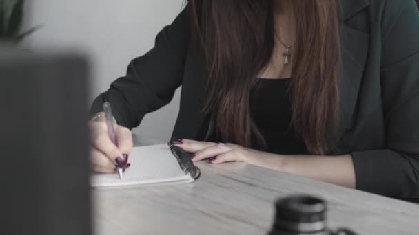 Business woman writing something in notebook. Start-up woman entrepreneur student studying writing note at workplace near computer. A womans hand writing down on a white blank notebook on table. - Footage, Video