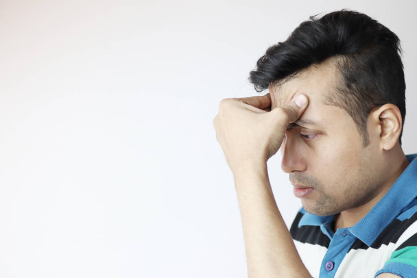 a young indian male with hands on forehead with a very worried expression isolated on white with copy space for text. - Photo, Image