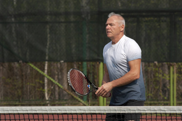 男は屋外コートでテニスをする - 写真・画像