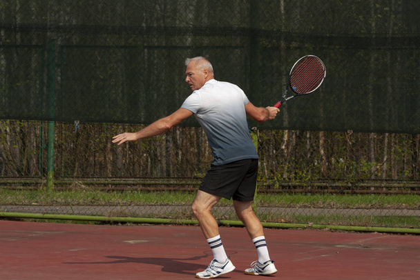 Άντρας που παίζει τένις στο υπαίθριο γήπεδο - Φωτογραφία, εικόνα