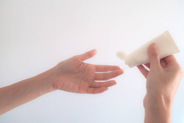 Close-Up Woman Hand Applying Moisturizing cream on White Backgro - Photo, image