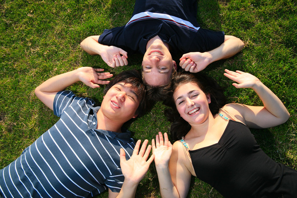 drie gelukkige vrienden liggend op groen gras - Foto, afbeelding