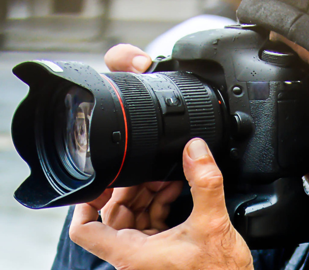 Kamera im Vordergrund mit der Hand des Fotografen - Foto, Bild