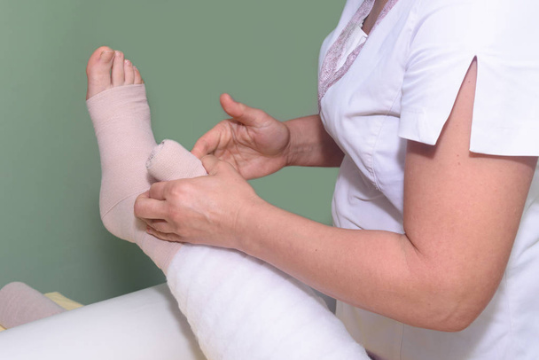 Управління лімфедемою: Розмивання ноги за допомогою багатошарових перев'язок для контролю Лімфедеми. Частина повної зневоднювальної терапії (cdt) і ручного лімфатичного дренажу (Mld).) - Фото, зображення
