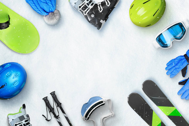 Akcesoria do sportów zimowych umieszczone na śniegu z przestrzenią do kopiowania w środku dla promocji tekstu lub logo. Góra, widok, płaski, leżeć. Koncepcja urlopu zimowego - Zdjęcie, obraz