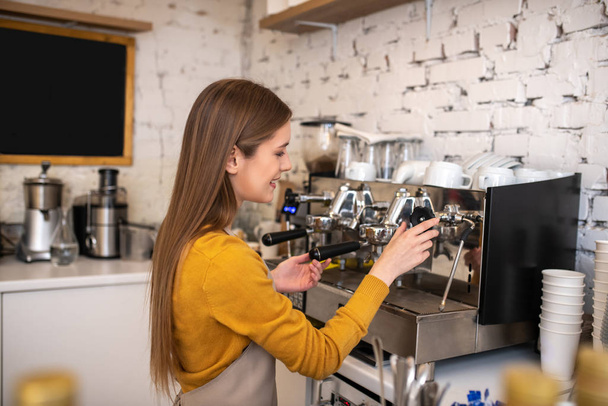 Mosolygós hosszú hajú barista professzionális kávéfőző géppel - Fotó, kép