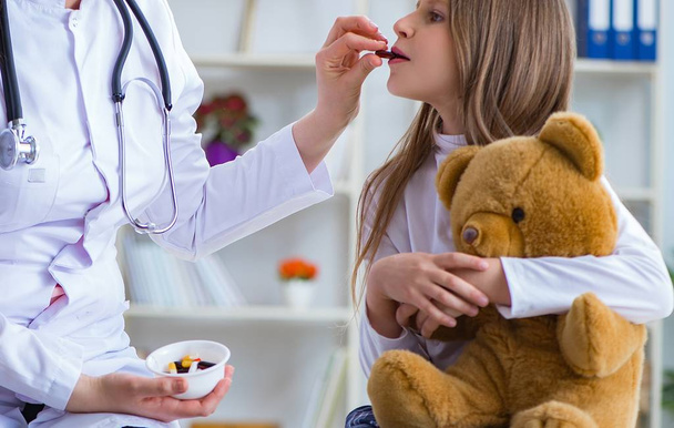 Woman female doctor examining little cute girl with toy bear - Foto, Bild