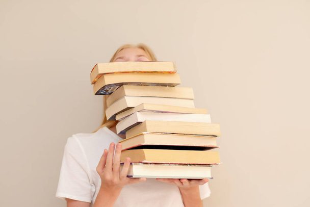Teini-ikäinen tyttö piilossa takana iso kasa kirjoja hän haluaa lukea. Opiskelija valmis opiskelemaan käsite
 - Valokuva, kuva