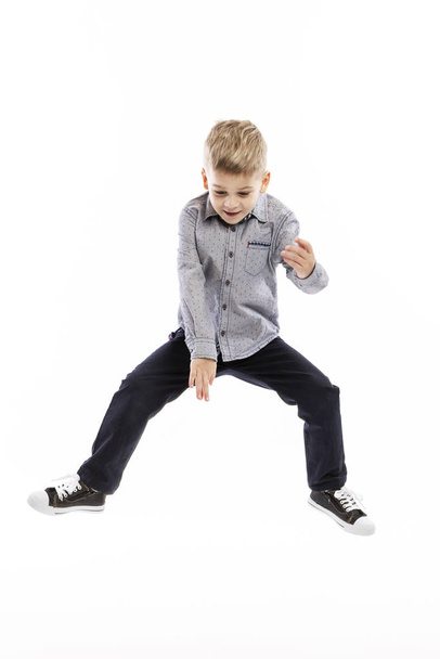 Little boy in a blue shirt and jeans is jumping. White background.  - Фото, зображення