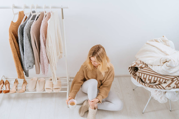 Young blond positive woman sitting in her light modern dressing room on the floor and drinks morning coffee. Top view. Fashion blog, website, social media hero header template - Foto, Imagem