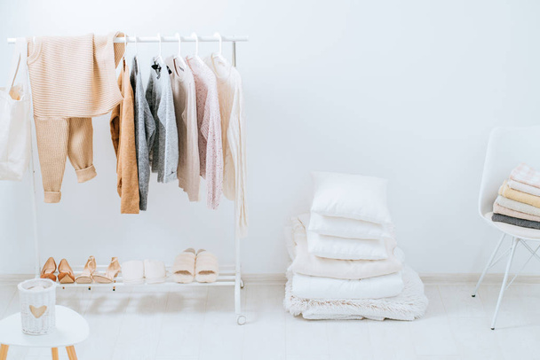 Scandinavian style, bedroom, bed, clothes rack in a modern light style. Female blouses and t-shirts on hanger on white background. Fashion blog, website, social media hero header template - Photo, image