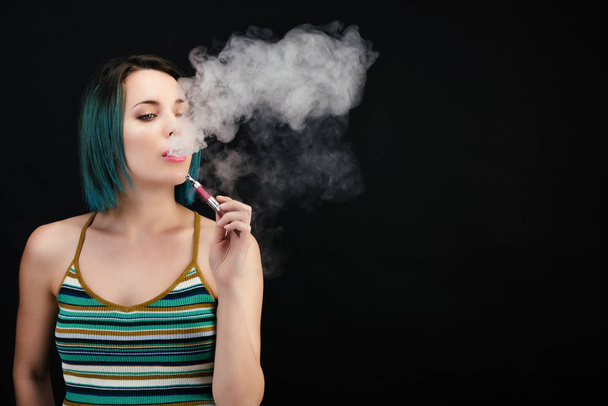 Nuori nainen höyryttää sähköisen savukkeen
 - Valokuva, kuva