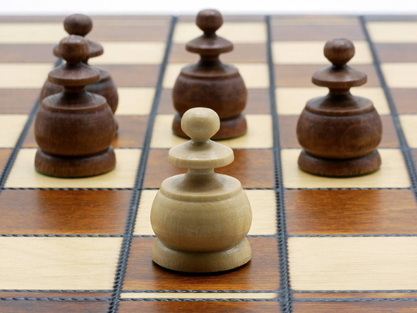 Underdog Concept: One White Pawn Standing Against Four Black Pawns - Foto, Bild