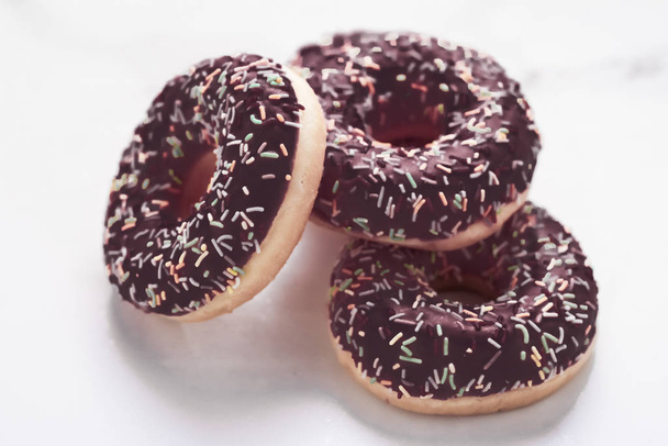 Пончики с глазурью, сладкий десерт из теста на мраморном столе b
 - Фото, изображение