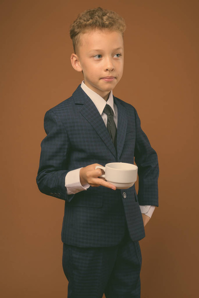 Young boy as businessman against brown background - Фото, зображення