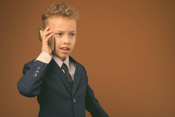 Young boy as businessman against brown background - Foto, immagini