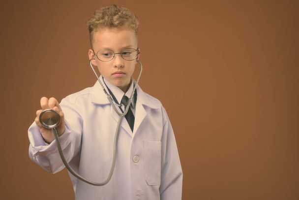 Студийный снимок мальчика в качестве врача на коричневом фоне
 - Фото, изображение