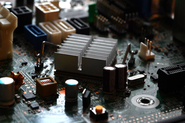 Extreme detail on the electronic components of a modern pc motherboard. Capacitors, resistor and other components in the foreground. Selective Focusing. - Photo, Image