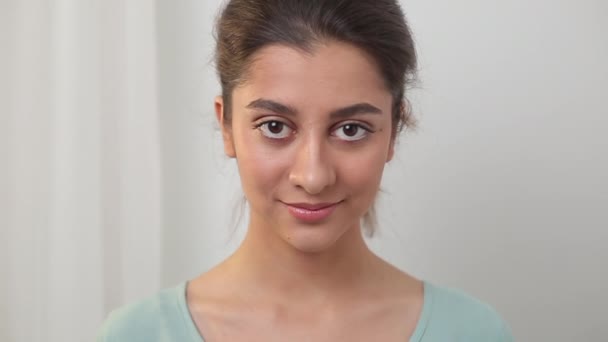 Indiase jonge vrouw glimlacht vriendelijk en kijkt naar de camera. Portret van een mooi brunette meisje. - Video
