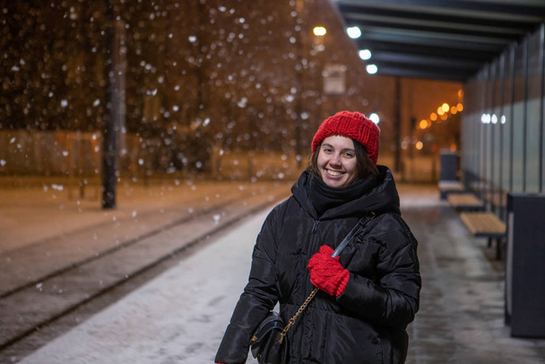 portret młodej uśmiechniętej kobiety na przystanku tramwajowym zimowa śnieżna noc - Zdjęcie, obraz