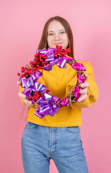 Young woman holding a bright valentines day wreath on pink backg - Photo, Image
