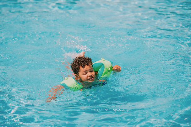 Bébé africain mignon garçon nageant dans la piscine avec anneaux de bras gonflables
 - Photo, image