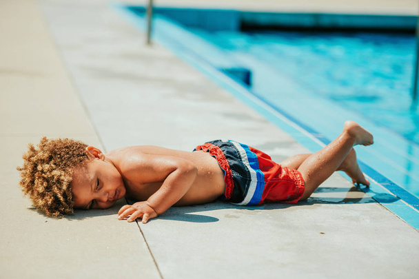 Väsynyt pikkupoika makaa uima-altaalla.
 - Valokuva, kuva
