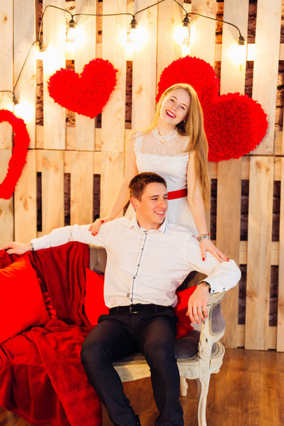 portrait of a couple near wooden wall with red hearts - Photo, Image