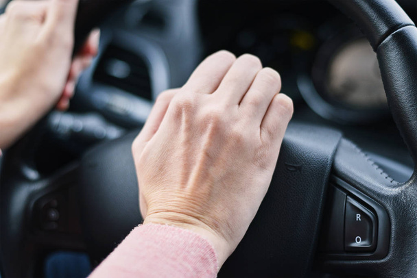 Рука водителя нажала кнопку рога на колесе автомобиля
 - Фото, изображение