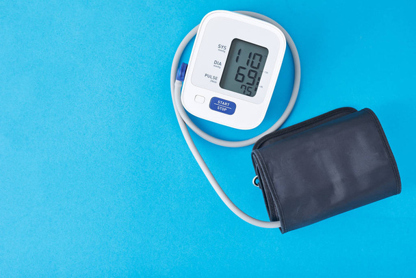 digitales Blutdruckmessgerät auf blauem Hintergrund, Nahaufnahme. Helathcare und medizinisches Konzept - Foto, Bild