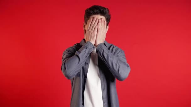 Young guy covers his face with hands from fatal disappointment, failure. Depressed lost man in shirt. Drama, emotions concept - Metraje, vídeo