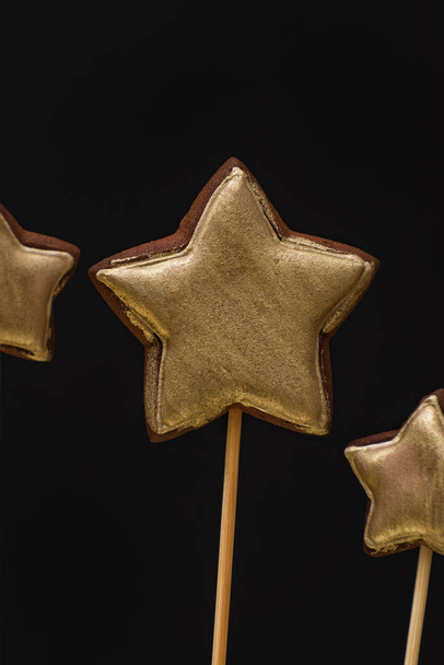 金色の星形のジンジャーブレッドクッキー黒の背景に棒 - 写真・画像
