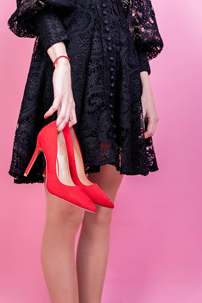 Сексуальная брюнетка в черном платье с красными туфлями на розовом фоне
 - Фото, изображение