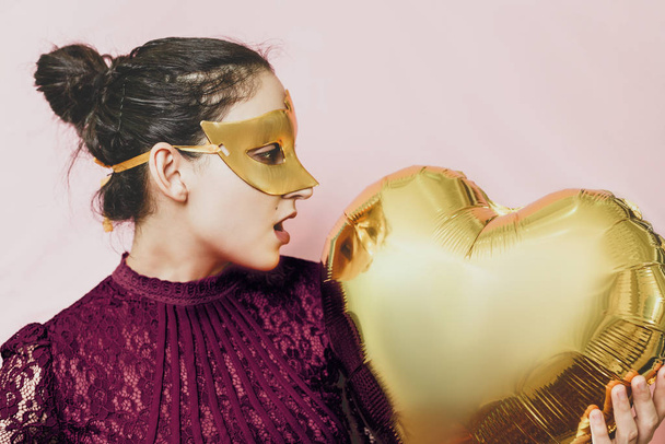 Femme portant un masque de mascarade et tenant un ballon à air en forme de coeur. Anniversaire, Anniversaire, Fête de la Saint Valentin, Fête des fêtes, Bal concepts de célébration
 - Photo, image