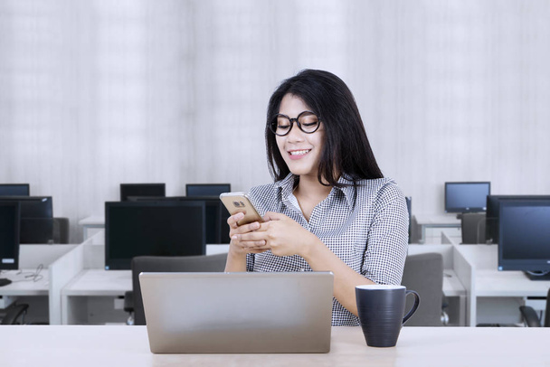 Woman texting someone while working on her desktop - Φωτογραφία, εικόνα