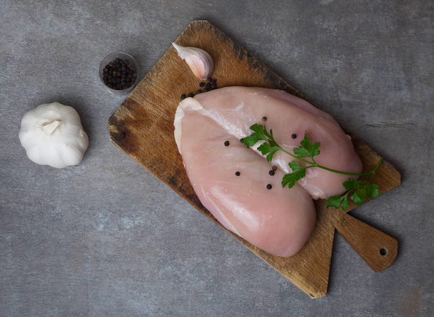 raw chicken breast fillet with spices on wooden board on white wooden table, top view, copy space - Foto, Bild