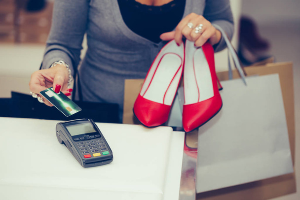 Mujer compra zapatos en la caja de la tienda, ella está utilizando la tarjeta de crédito
  - Foto, Imagen
